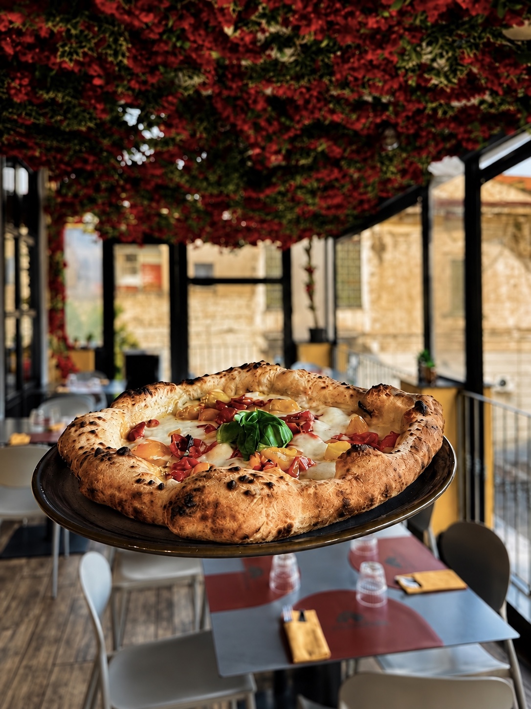 Una pizza di La Terrazza nella sala con il soffitto di fiori rossi