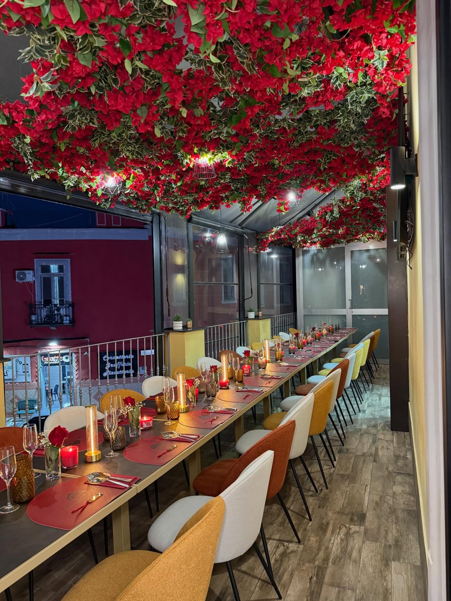La terrazza del ristorante con tavoli apparecchiati e fiori rossi sul soffitto
